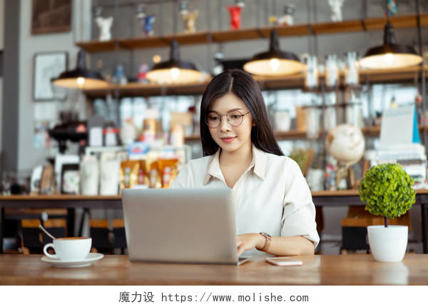 快乐自由职业者亚洲妇女工作使用数字笔记本电脑打字键盘在共同工作空间或咖啡馆.